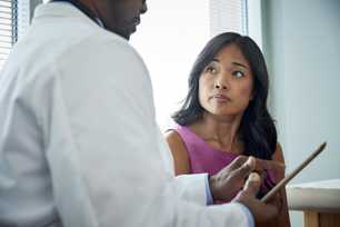 lady looks to the doctor as he points to a screen of a tablet